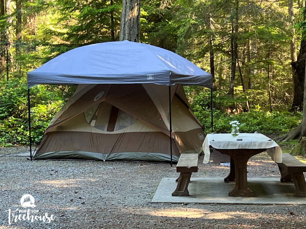 big camping tent with gazebo over top for rain next to a picnic table